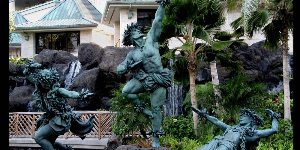 “Kaha ka ‘Io me na Makani”(The Hawk soars with the Winds)“Ku  Makani”(Rising Wind)“Kaha ka ‘Io”(The Hawk Soars)“Ka Leo o Haukani”(The Voice of the Wind)17’x 21’x 9’ in bronze and stoneGracefully striding the edge of a waterfall, these three, twice life size figures in bronze are dancing hula kahiko, the ancient style of Hawaiian dance. The two female dancers, the spirits of the wind, represent the dance and chant of Hawaiian hula. Together they are the winds that uplift the mighty ‘Io , the Hawaiian Hawk, the central male dancer, who represents the spirit of Hawai’i poised to take flight.These images pay tribute to the importance of dance, chant and song in the rebirth and growth of Hawaiian culture. Together they celebrate the power of the hula connecting us with the spirit of the land, the Aina that is Hawaii.Commissioned by Hilton Hawaiian VillageCompleted May, 2001